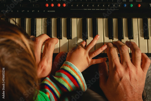 Father and child playing piano together
 photo