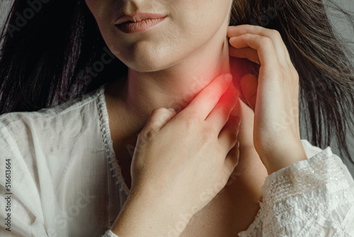 Woman touches neck throat with hand, tonsillitis and sore throat photo