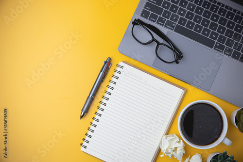 Business  technology  study  and learning concept. Copy space on office workspace yellow desk table with laptop  coffee  a pen  notebook  plant. flat lay equipment office on yellow background.