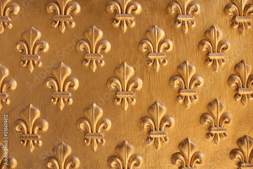 Fleur de Lis pattern painted gold over wooden texture for background. Repeated fleur-de-lis pattern. photo