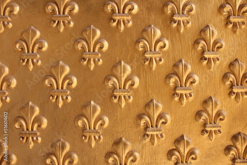 Fleur de Lis pattern painted gold over wooden texture for background. Repeated fleur-de-lis pattern.