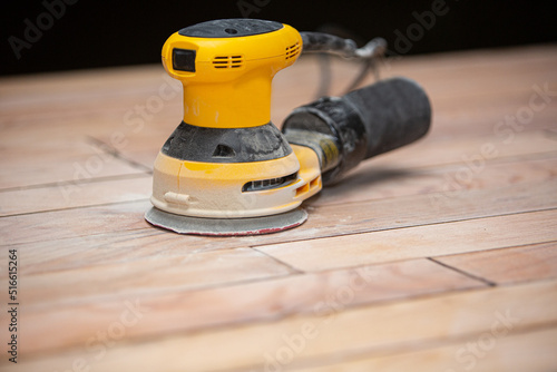 electric orbital sander on wooden oak floor