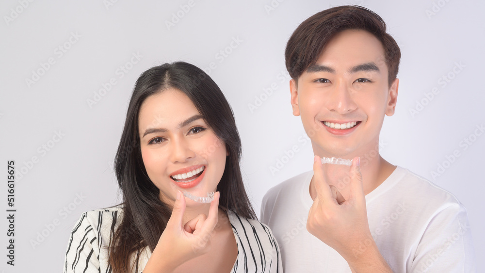 Young smiling man amd woman holding invisalign braces over white background studio, dental healthcare and Orthodontic concept.. Young smiling man amd woman holding invisalign braces over white background studio, dental healthcare and Orthodontic concept..