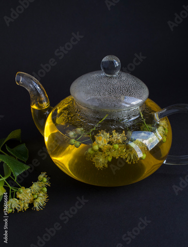 Tea with linden flower in the glass teapotn on the black background. Location vertical. photo