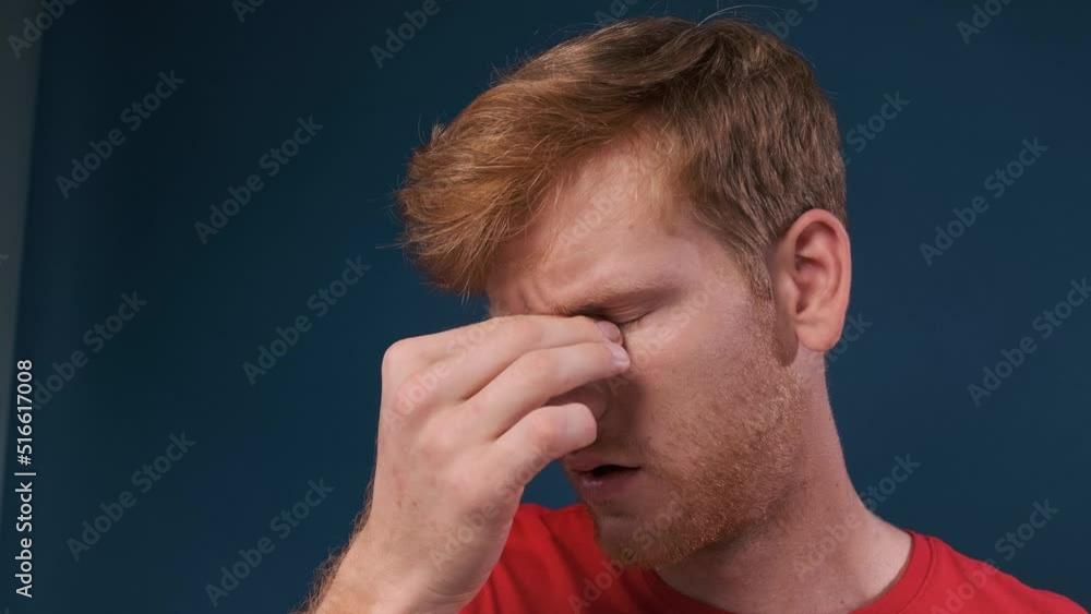 Caucasian man with glasses tired rubbing eyes feeling fatigue and headache. stress and frustration concept isolated on dark blue background Caucasian man with glasses tired rubbing eyes feeling fatigue and headache. stress and frustration concept isolated on dark blue background