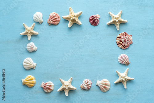 Starfishes and seashells laid out in the frame on blue wooden background.