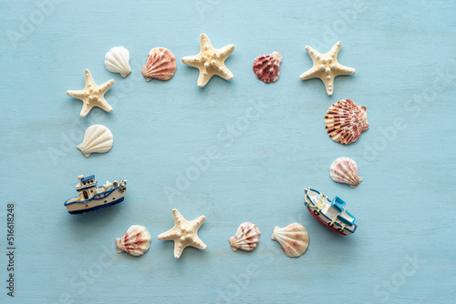 Starfishes, seashells, decorative boats laid out in the frame on blue wooden background.