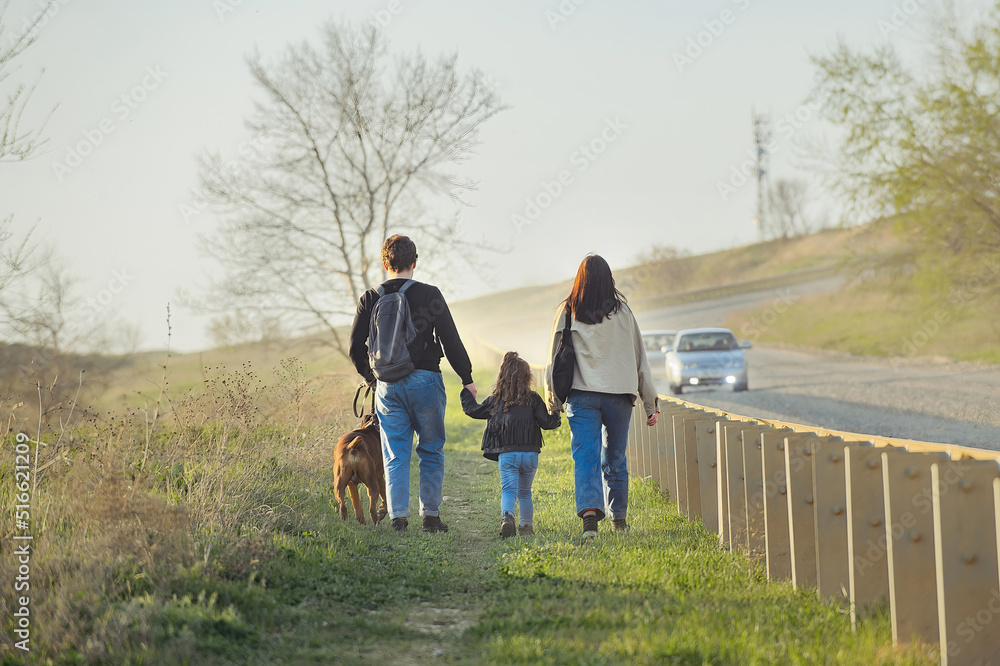 a family of three and with them their big red dog of the German boxer breed make a hike along the highway a family of three and with them their big red dog of the German boxer breed make a hike along the highway