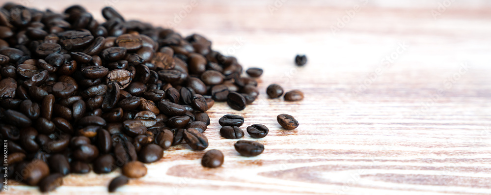 Aromatic coffee beans on the wooden background with copy space. Banner. Selective focus.