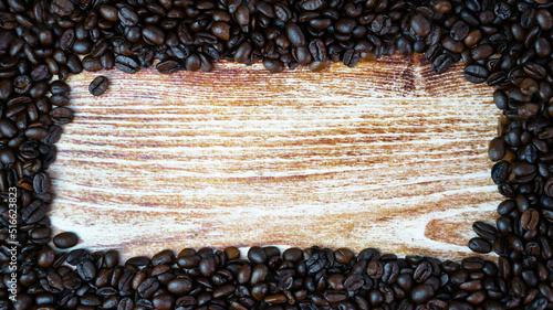 Frame of coffee beans on a wooden background. Coffee day. Place for yur text. Top view. Selective focus. photo