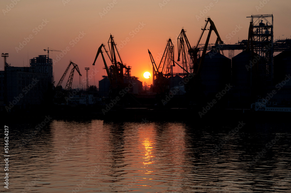 Odesa sea port gantry crane silhouettes at sundown sky background