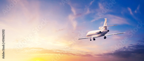 Modern corporate business jet during flight against the background of the sunset sky. Horizontal banner with free copy space for text photo