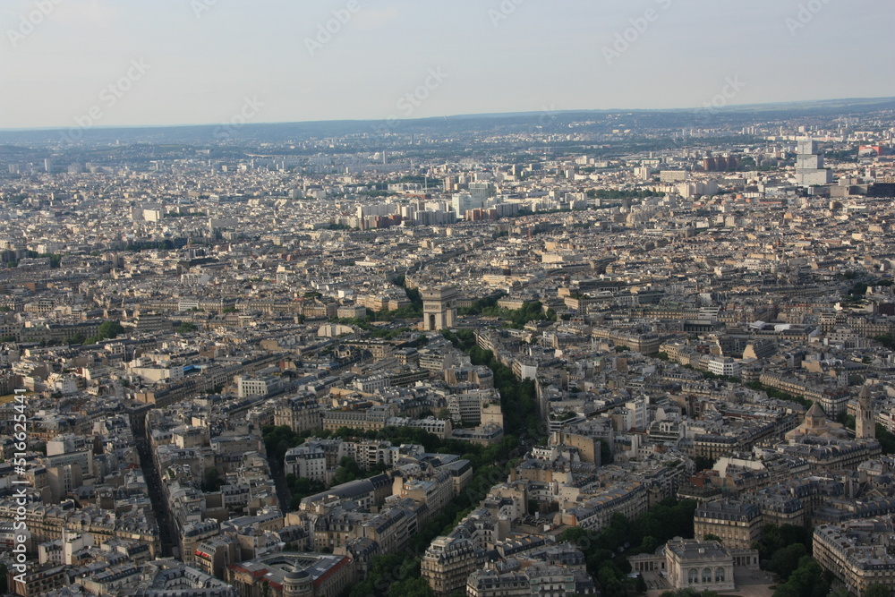 Überbick über Paris mit l'Arc de Triomph (Triumpfbogen) im Zentrum, welches einen großen Kreisverkehr darstellt, von welchem viele Straßen münden.