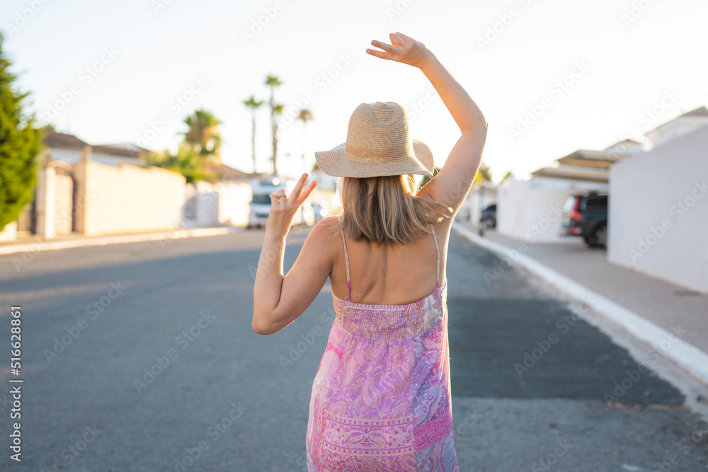Back view summer woman with straw hat and a dress in the street outdoors. Summertime concept.