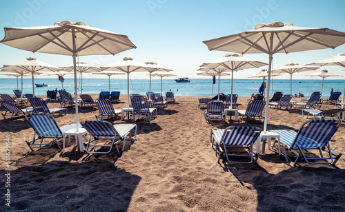 Fototapeta Naklejka Na Ścianę i Meble -  Sunshades with loungers on sandy beach at resort Faliraki in Rhodes island at Greece