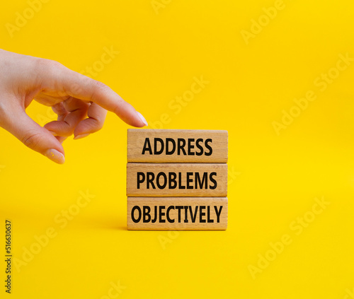Address Problems Objectively symbol. Wooden blocks with words Address Problems Objectively. Beautiful yellow background. Businessman hand. Business and Address Problems Objectively concept. Copy space