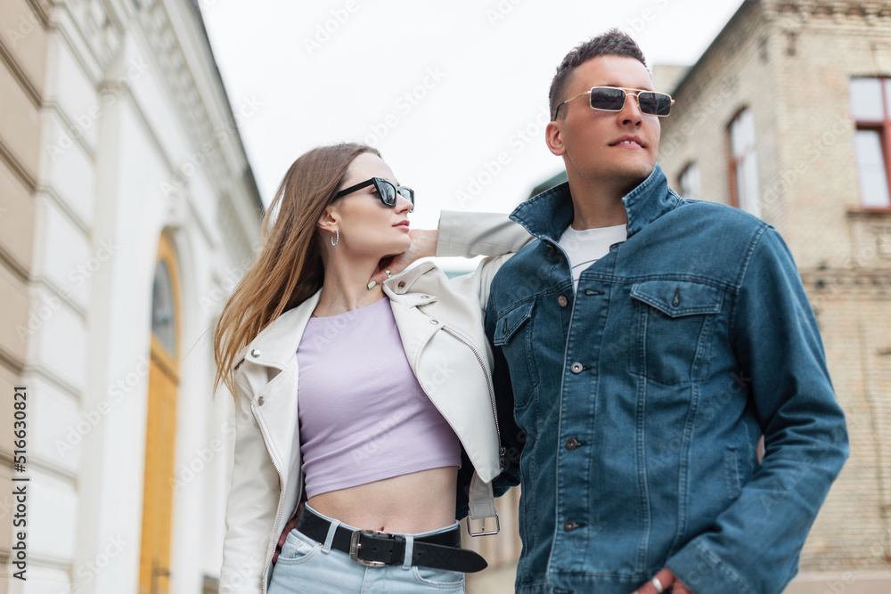 Stylish beautiful models woman and man with sunglasses in fashionable casual outfit with leather jacket and jeans jacket walking in the city Stylish beautiful models woman and man with sunglasses in fashionable casual outfit with leather jacket and jeans jacket walking in the city