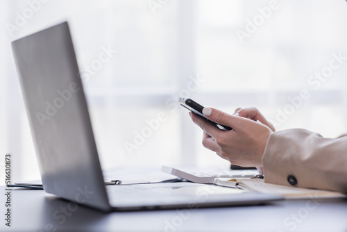 Asian businesswoman using mobile phone indoor, Asian businesswoman working on laptop in modern office.