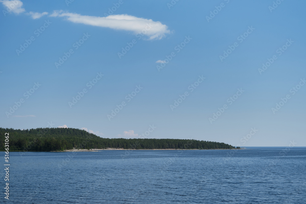 View from island Koyonsaari, Republic of Karelia on Lake Ladoga and mixed green forest in distance. Sunny warm summer day, blue sky. Concept of traveling in Russia.