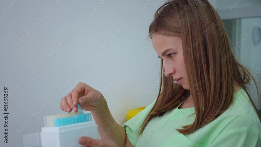 Side view portrait of focused genius young female scientist checking test tubes in box in laboratory. Concentrated intelligent Caucasian woman thinking working in lab indoors Side view portrait of focused genius young female scientist checking test tubes in box in laboratory. Concentrated intelligent Caucasian woman thinking working in lab indoors