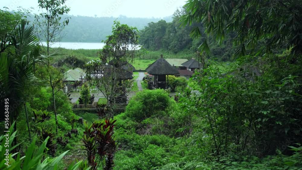 Indonesian temple with roofs standing in a field near a forest Indonesian temple with roofs standing in a field near a forest