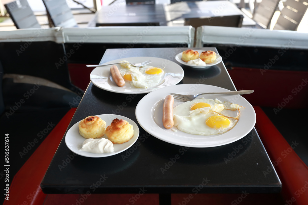 Plates with fried eggs and cheesecakes on table Plates with fried eggs and cheesecakes on table