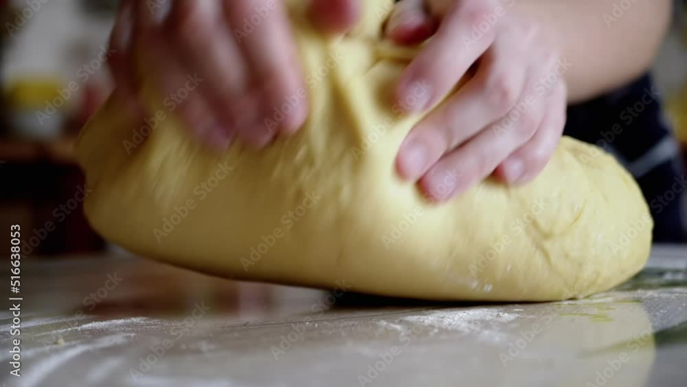 Female Hands are Kneading Yeast Dough, Tossing on a Table Sprinkled with Flour. Yellow, smooth dough for making bread, buns. Cooking sweet delicious pastries for the family at home. Slow-motion. Female Hands are Kneading Yeast Dough, Tossing on a Table Sprinkled with Flour. Yellow, smooth dough for making bread, buns. Cooking sweet delicious pastries for the family at home. Slow-motion.