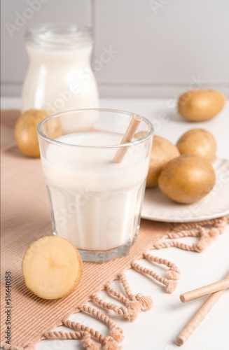 A glass with potato milk on the table with the potato tubers. Vegan trend in healthy eating. Alternative plant milk