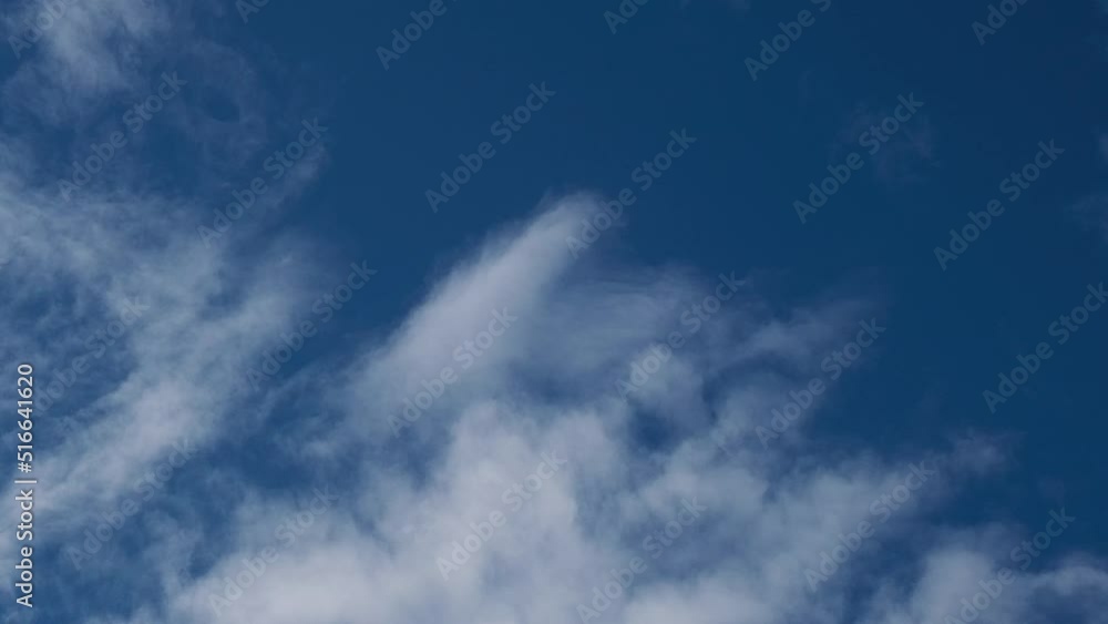 Light white clouds fly across a bright blue sky. Clear sky at sunny summer afternoon. Summer cloudscape background. Copy space Light white clouds fly across a bright blue sky. Clear sky at sunny summer afternoon. Summer cloudscape background. Copy space