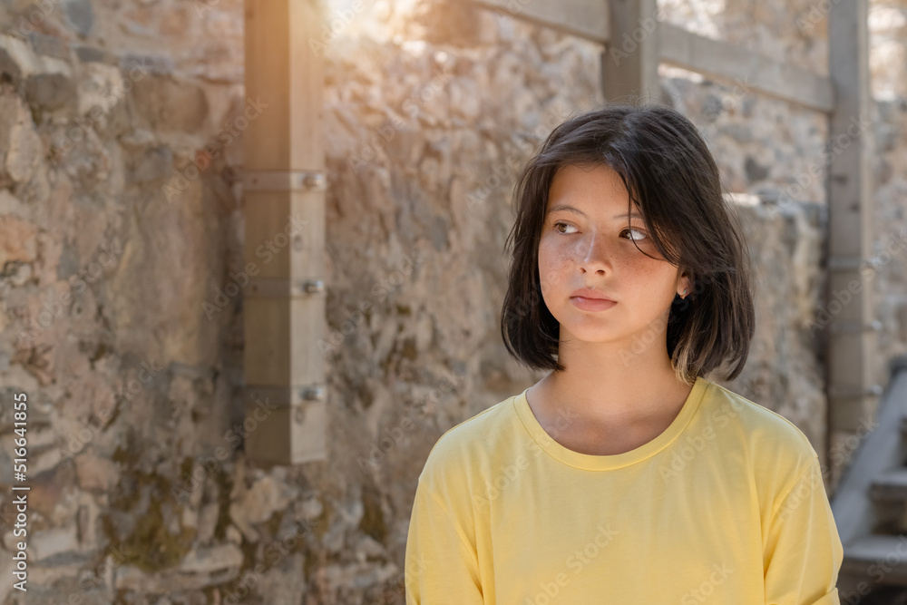 Portrait of a young girl posing against a stone wall.