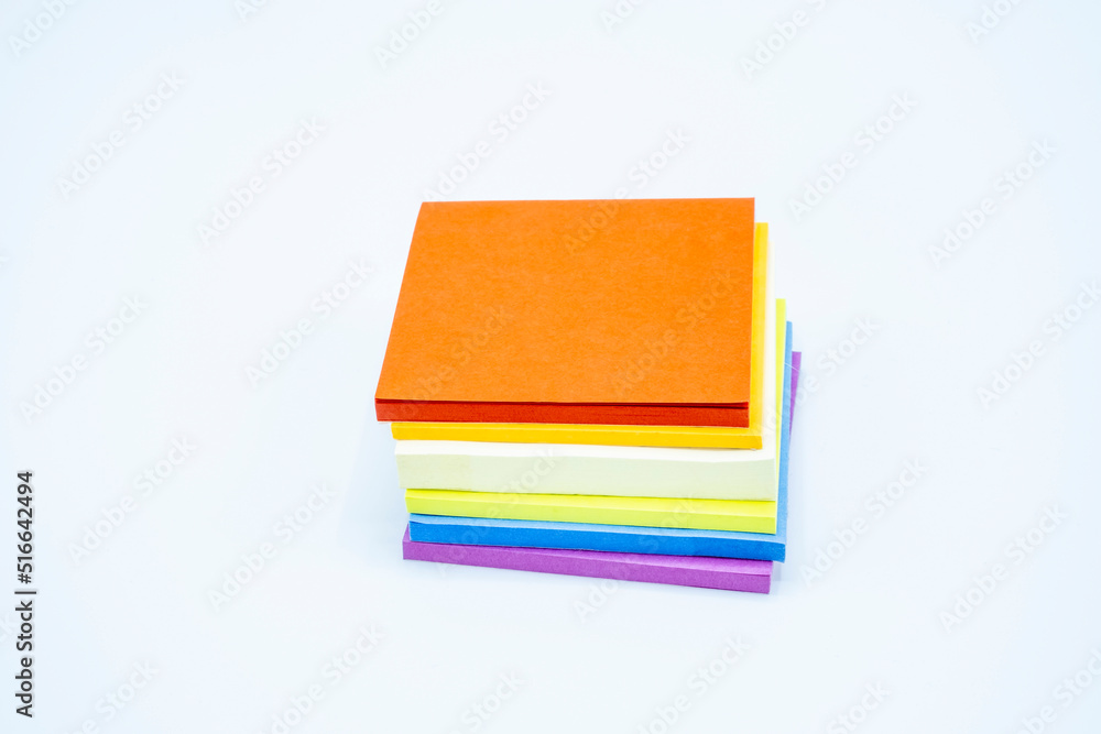Sticky note pads stacked in rainbow order on white tabletop Sticky note pads stacked in rainbow order on white tabletop