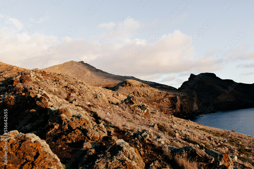 Wild nature. Rocky red mountains on the background of Atlantic ocean in sunlight. Beautiful view. 