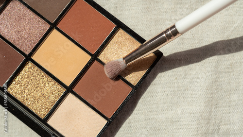 The makeup brush lies on the eyeshadow palette. Multi-colored palette of shades for makeup, face cosmetics.