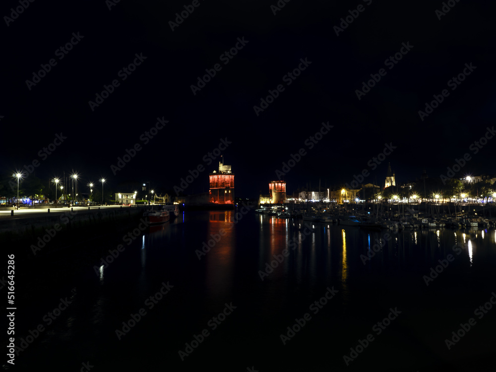 La Rochelle, France June 2022. Night photo of the port of La Rochelle, light illumination on two towers and yachts standing in the port