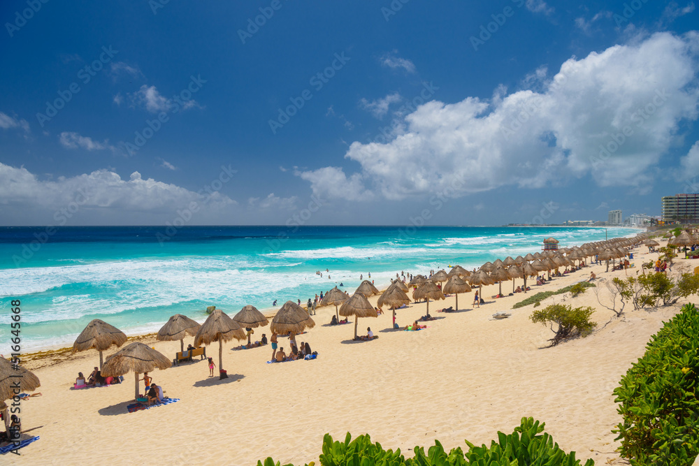 Umbrelas on a sandy beach with azure water on a sunny day near Cancun, Mexico