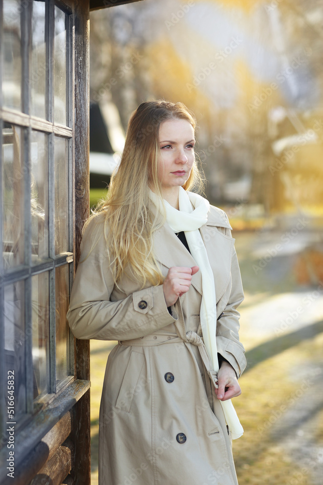 young blond beautiful woman with long hair wearing trench coat closeup street portrait