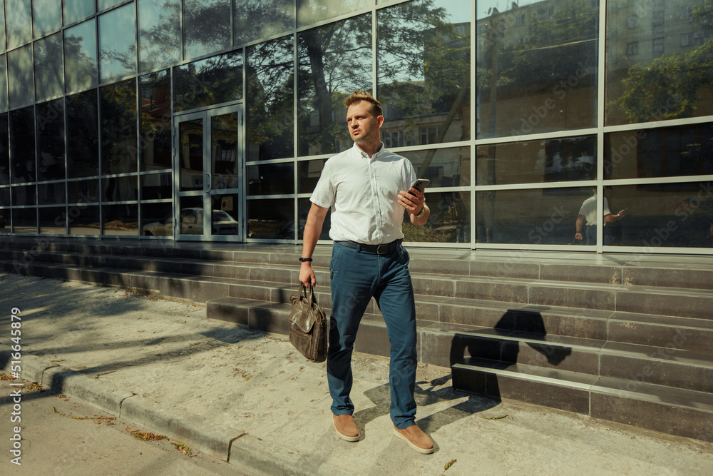 A young businessman man with a mobile phone near a glass building A young businessman man with a mobile phone near a glass building