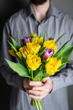 Bouquet of tulips in male hands. Yellow and purple tulips. Gift, woman's day, mother's day concept