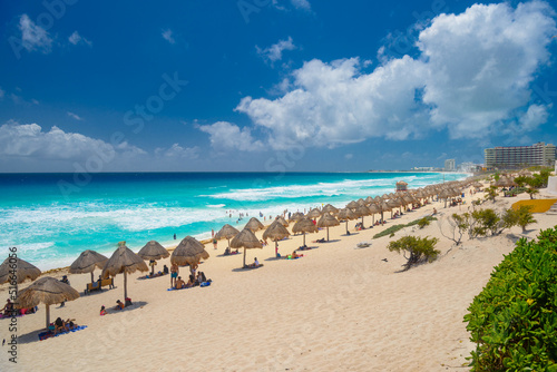 Umbrelas on a sandy beach with azure water on a sunny day near Cancun, Mexico © Eagle2308