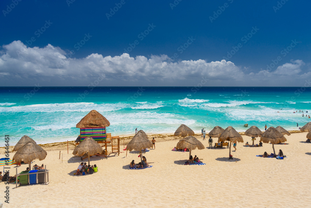 Umbrelas on a sandy beach with azure water on a sunny day near Cancun, Mexico Umbrelas on a sandy beach with azure water on a sunny day near Cancun, Mexico