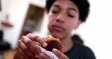 Child eating burger. Young boy taking a bite of hamburger