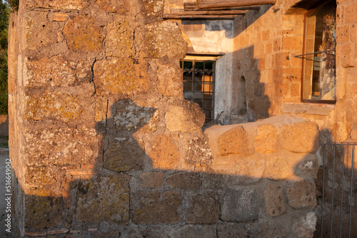 Shadow of a woman in hat on ancient building wall of stones in romantic summer evening