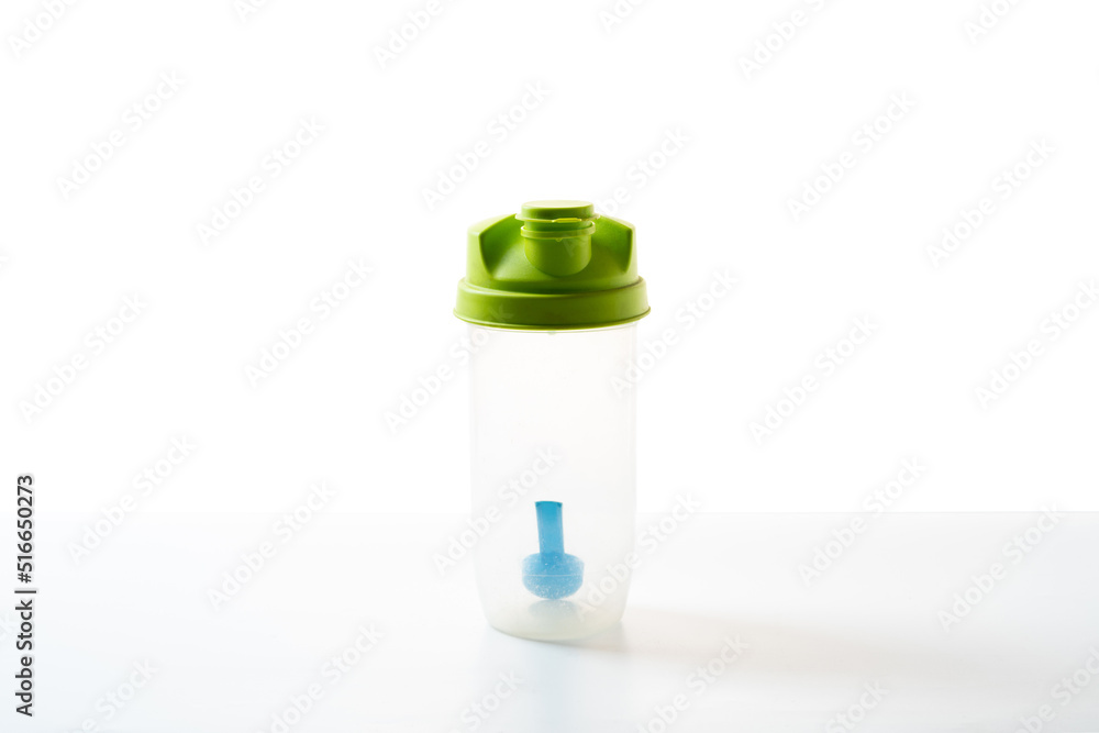 Empty plastic shaker with measuring spoon. Sports shaker on a white background. Isolated shaker. Empty plastic shaker with measuring spoon. Sports shaker on a white background. Isolated shaker.