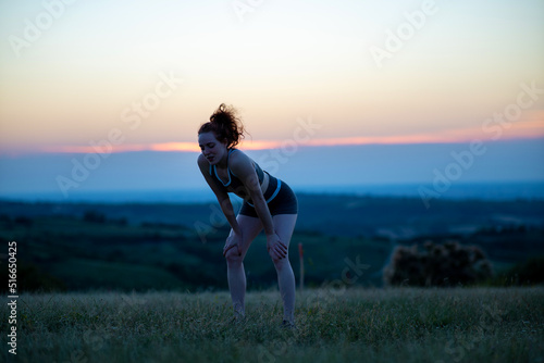 Silhouette of young woman resting during running outside.Sporty young woman running on road in sunset.