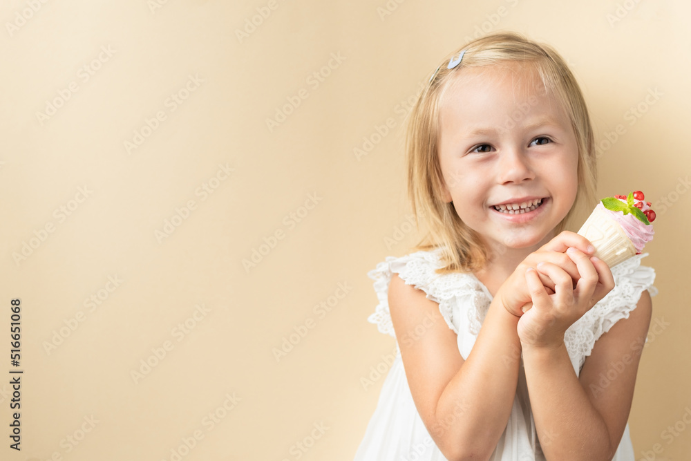 Beautiful little caucasian girl with blonde hair in a white dress enjoying berry flavored waffle cone ice cream on the beige background Beautiful little caucasian girl with blonde hair in a white dress enjoying berry flavored waffle cone ice cream on the beige background