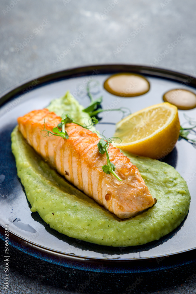 Salmon steak on the grill with mashed potatoes with spinach with lemon on blue plate on grey table macro close up vertical Salmon steak on the grill with mashed potatoes with spinach with lemon on blue plate on grey table macro close up vertical