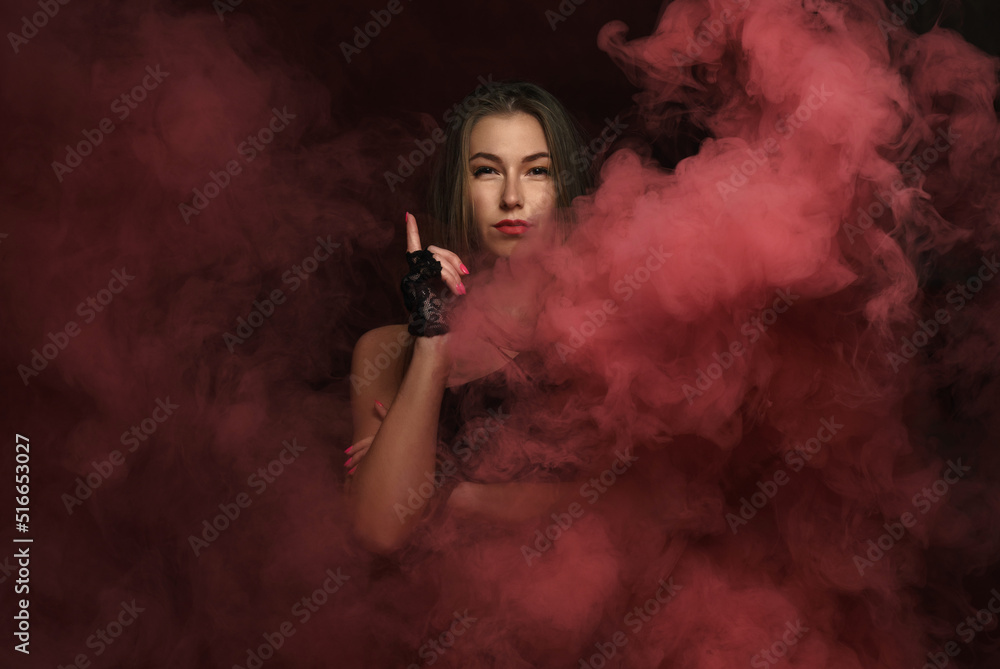 Portrait of strong woman wearing black gloves standing in red smoke with copy space