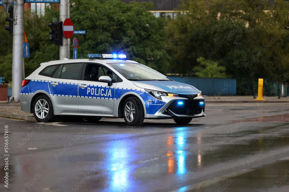 Radiowóz polska policja wieczorem z sygnalizatorem  błyskowy niebieski na dachu. Nocny patrol.  - obrazy, fototapety, plakaty 