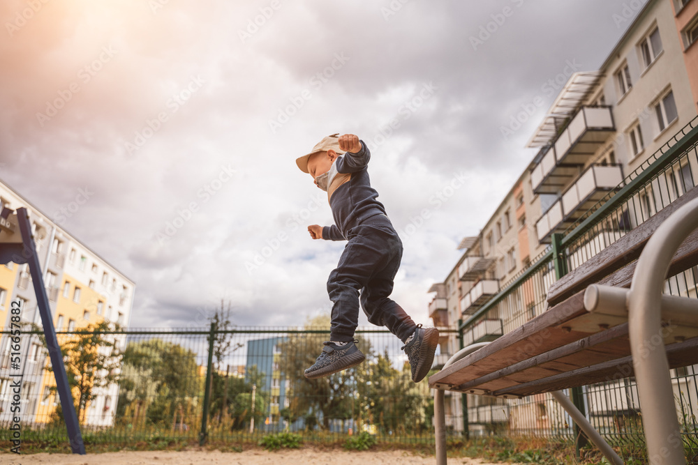 Child jumping from the bench in kindergarten. Happy childhood concept. Healthy summer activity for children Child jumping from the bench in kindergarten. Happy childhood concept. Healthy summer activity for children