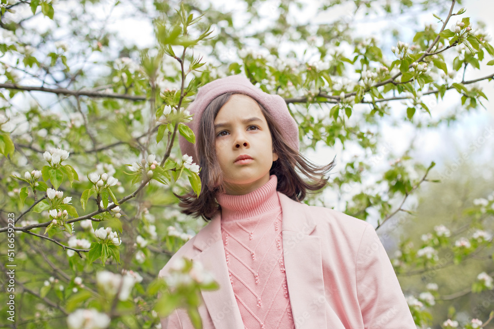 Portrait of little girl stands in a blooming white apple tree in the park. Portrait of little girl stands in a blooming white apple tree in the park.